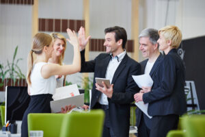 Successful team of business people giving high five working in strengths-based culture office.